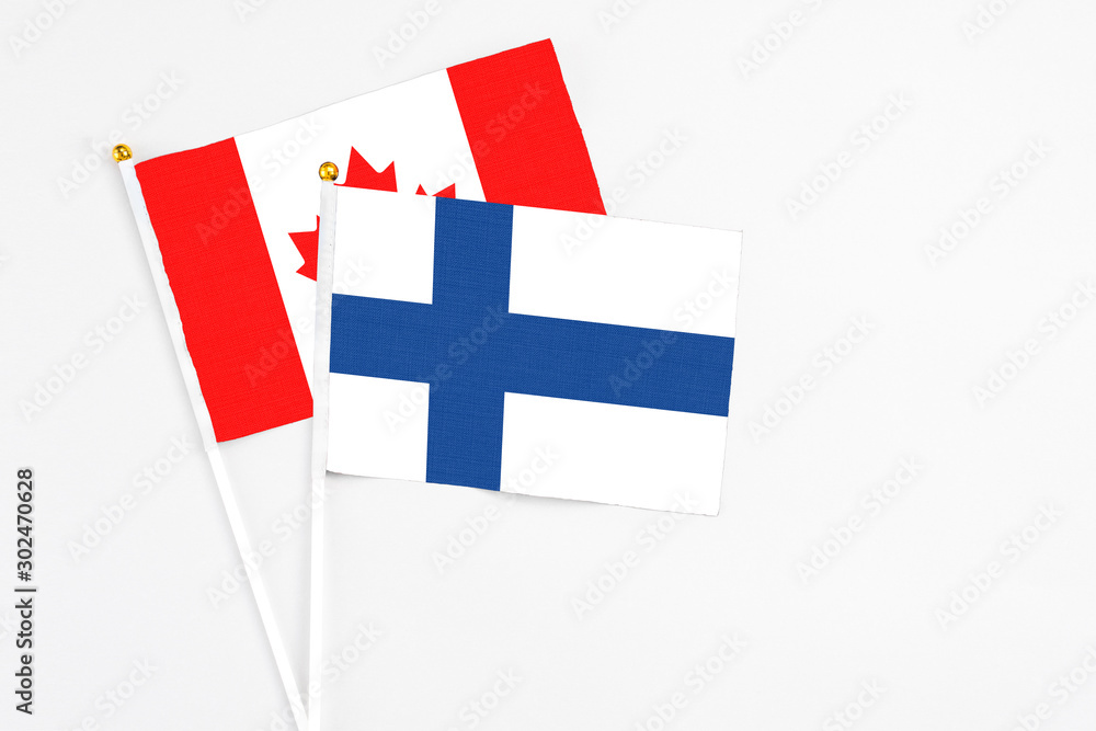 Finland and Canada stick flags on white background. High quality fabric, miniature national flag. Peaceful global concept.White floor for copy space.