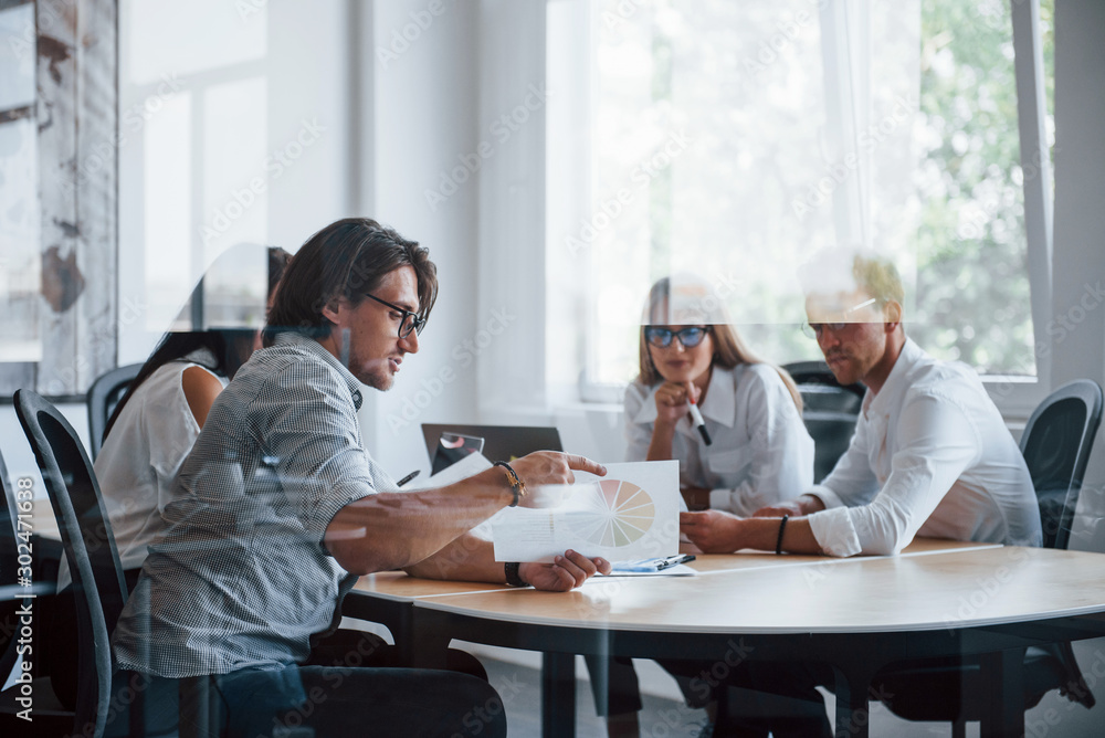 Some documents on the table and in hands. Young business people in formal clothes working in the office Some documents on the table and in hands. Young business people in formal clothes working in the office