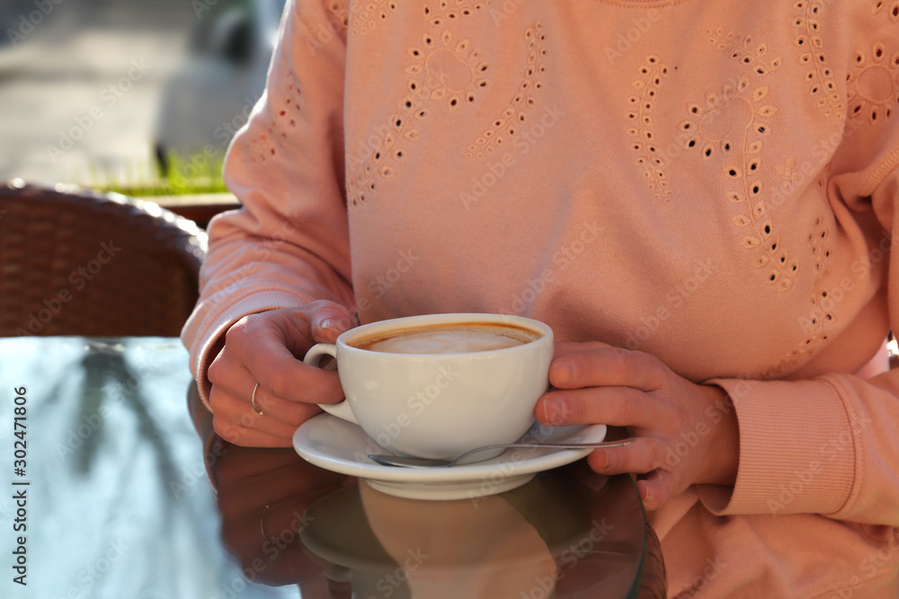 Woman with cup of fresh aromatic coffee at table in cafe Woman with cup of fresh aromatic coffee at table in cafe