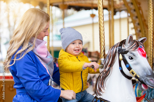 Mom with a cheerful baby on a carousel.Little son with mom in the park.