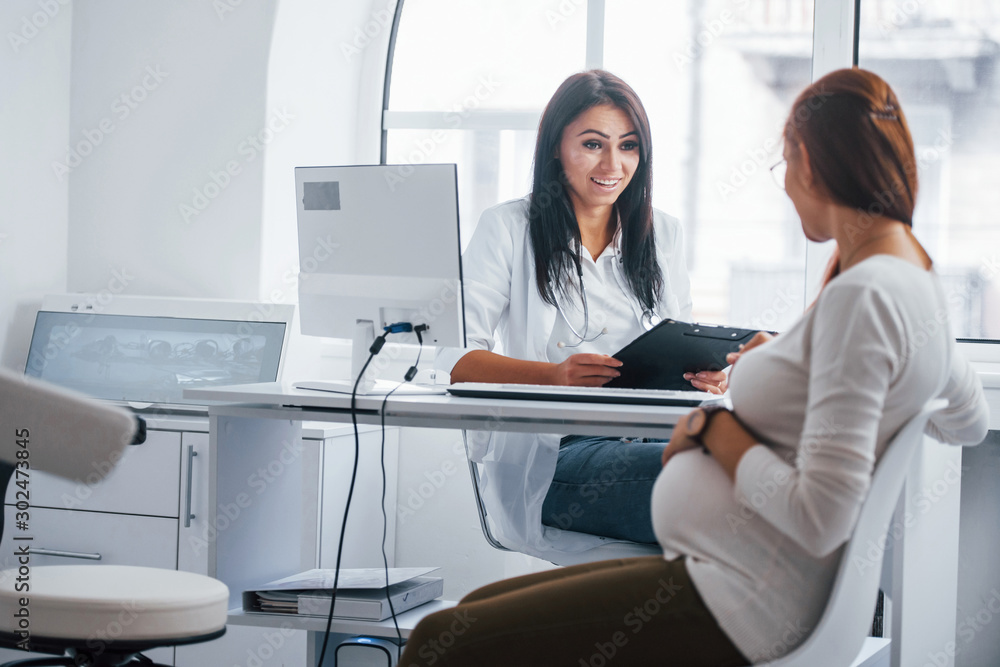 Active conversation. Pregnant woman have consultation with obstetrician indoors Active conversation. Pregnant woman have consultation with obstetrician indoors