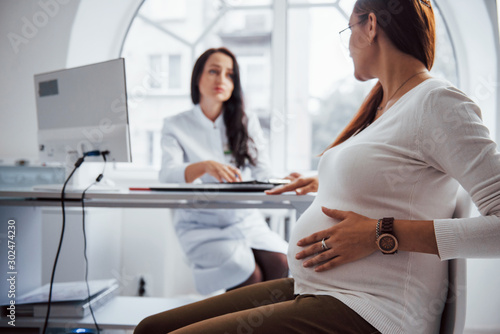 Pregnant woman have consultation with obstetrician indoors photo