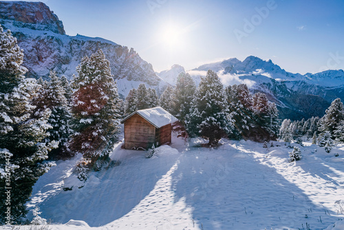 Wooden hut in Alpine mountains in deep snow during sunny winter day / South Tyrol region during winter