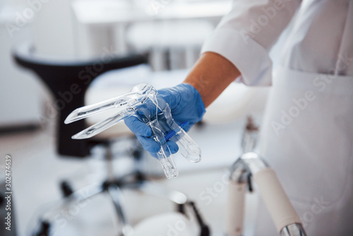 Close up view of female doctor hands that holds speculum instrument photo