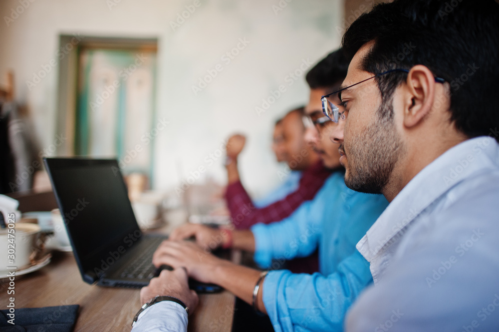 Group of four south asian men's posed at business meeting in cafe. Indians work with laptops together using various gadgets, having conversation. Group of four south asian men's posed at business meeting in cafe. Indians work with laptops together using various gadgets, having conversation.