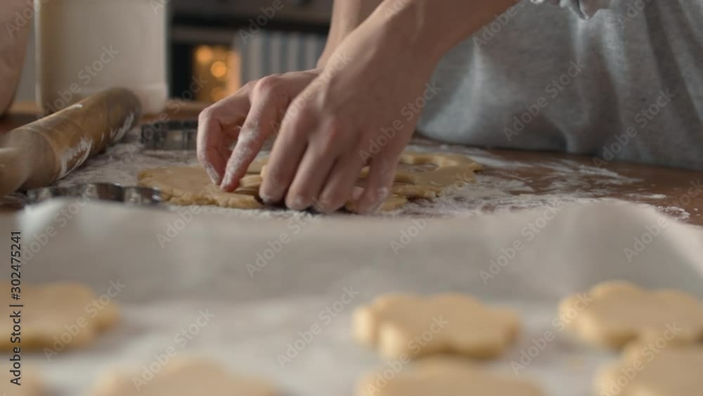 Close up of unrecognizable housewife hands making cookies of flower shape using steel baking tin Close up of unrecognizable housewife hands making cookies of flower shape using steel baking tin