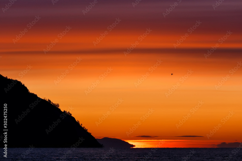 Colorful sunrise at Baikal lake with flying bird