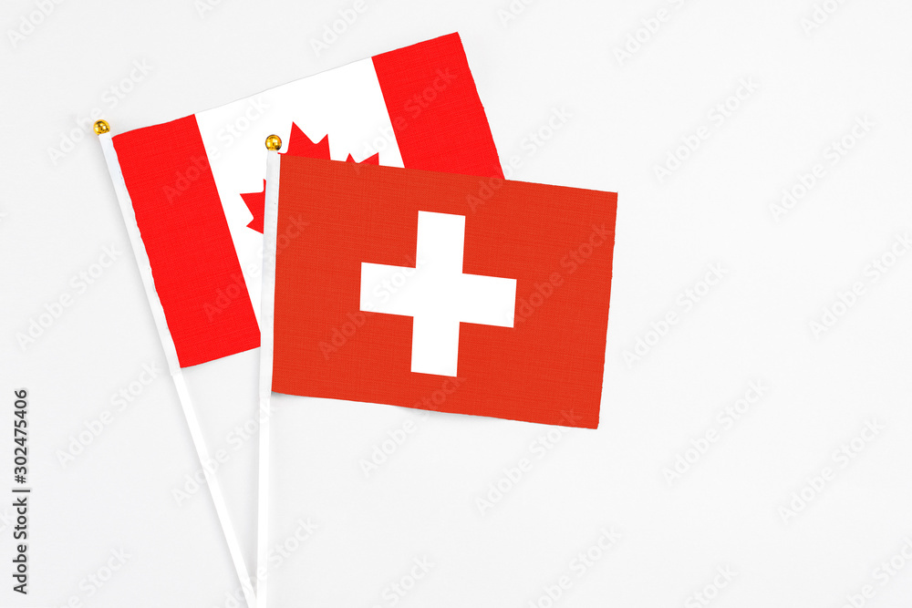 Switzerland and Canada stick flags on white background. High quality fabric, miniature national flag. Peaceful global concept.White floor for copy space.