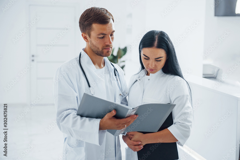 Doctor and brunette nurse stands in the hospital and talking at the work Doctor and brunette nurse stands in the hospital and talking at the work
