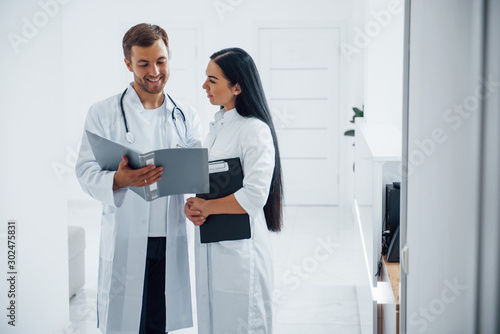 Doctor and brunette nurse stands in the hospital and talking at the work