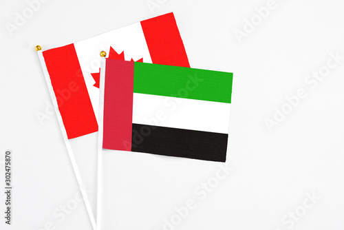 United Arab Emirates and Canada stick flags on white background. High quality fabric, miniature national flag. Peaceful global concept.White floor for copy space.