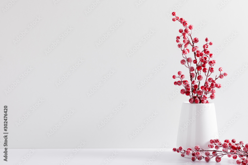 Fototapeta Winter composition of white branches, red berries and leaves with sparkles in vase on white background. Christmas, New Year, winter concept. Front view, copy space