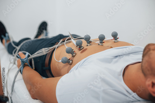 Man lying on the bed in the clinic and getting electrocardiogram test photo