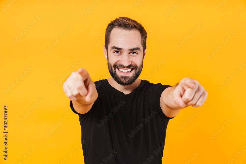 Image of cheerful man wearing t-shirt smiling and pointing fingers at you Image of cheerful man wearing t-shirt smiling and pointing fingers at you