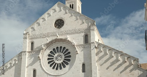 Façade of the church of San Nicola in Bari in limestone. Church with light stone walls with the blue sky background with clouds.