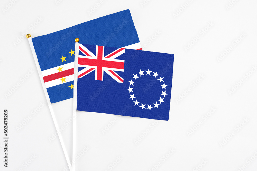 Fototapeta premium Cook Islands and Cape Verde stick flags on white background. High quality fabric, miniature national flag. Peaceful global concept.White floor for copy space.