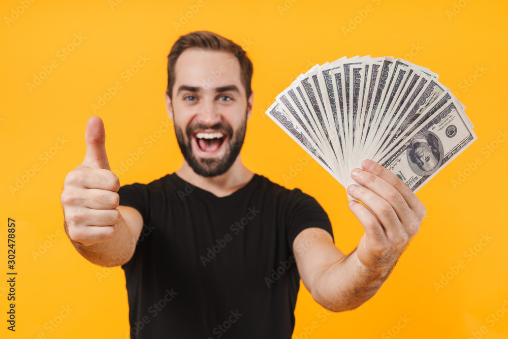 Image of unshaved man wearing t-shirt smiling and holding money cash Image of unshaved man wearing t-shirt smiling and holding money cash