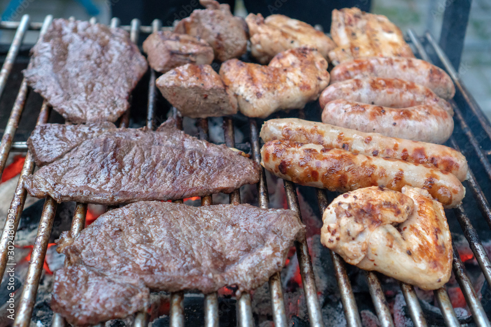 Assorted delicious grilled meat and bratwurst over the coals on a barbecue. Assorted delicious grilled meat and bratwurst over the coals on a barbecue.