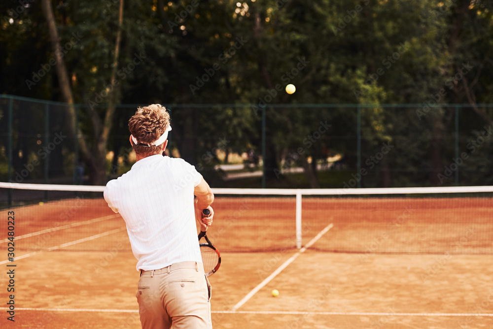 Young tennis player in sportive clothes is on the court outdoors