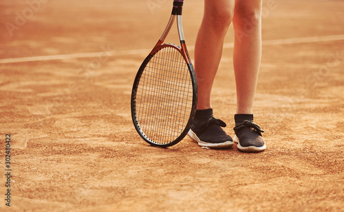 Legs and racket of female player that stands in the court at daytime © standret