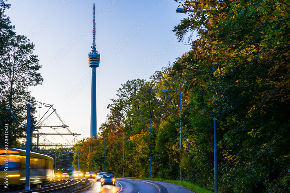 Germany, Famous television tower of stuttgart city behind a train and street full of traffic decorated by colorful autumn foliage trees in autumn season