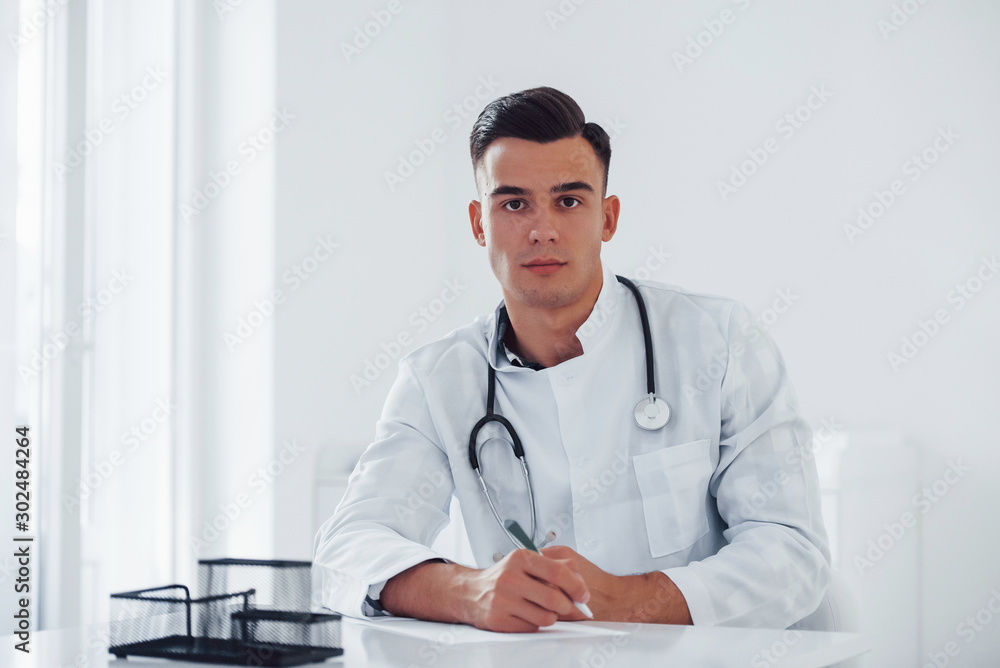 Young stylish male doctor with stethoscope is in clinic at daytime Young stylish male doctor with stethoscope is in clinic at daytime