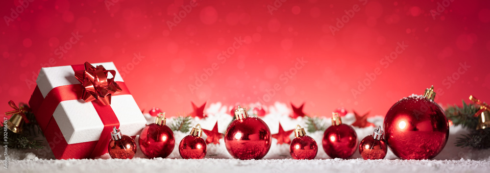 Panoramic image of gift box and red christmas balls on snow - obrazy, fototapety, plakaty 