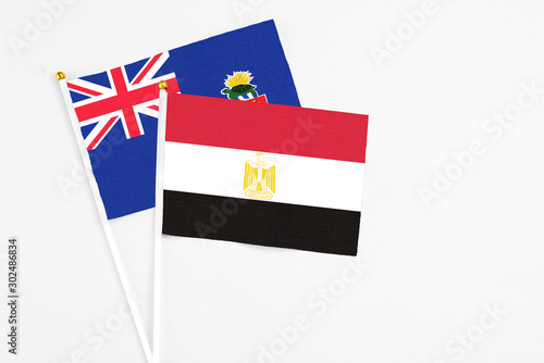 Egypt and Cayman Islands stick flags on white background. High quality fabric, miniature national flag. Peaceful global concept.White floor for copy space.