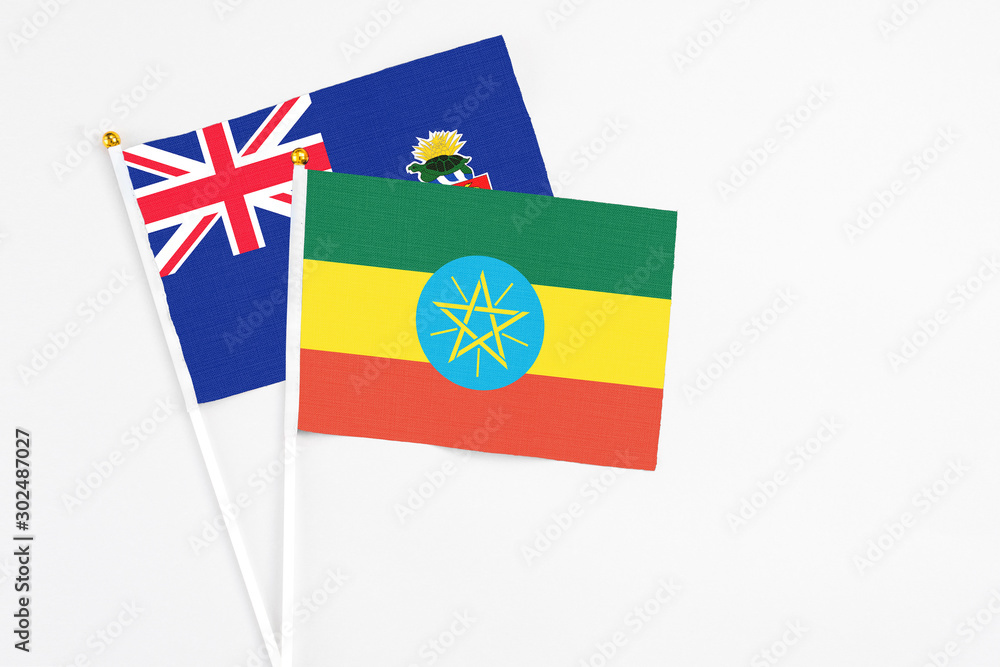 Ethiopia and Cayman Islands stick flags on white background. High quality fabric, miniature national flag. Peaceful global concept.White floor for copy space.
