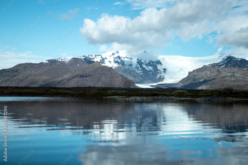 View of a glacier in the mountains and reflective lake along the ring road of Iceland's east coast