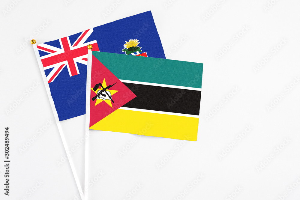 Mozambique and Cayman Islands stick flags on white background. High quality fabric, miniature national flag. Peaceful global concept.White floor for copy space. Mozambique and Cayman Islands stick flags on white background. High quality fabric, miniature national flag. Peaceful global concept.White floor for copy space.