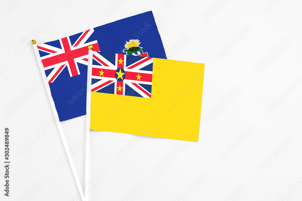 Niue and Cayman Islands stick flags on white background. High quality fabric, miniature national flag. Peaceful global concept.White floor for copy space. Niue and Cayman Islands stick flags on white background. High quality fabric, miniature national flag. Peaceful global concept.White floor for copy space.