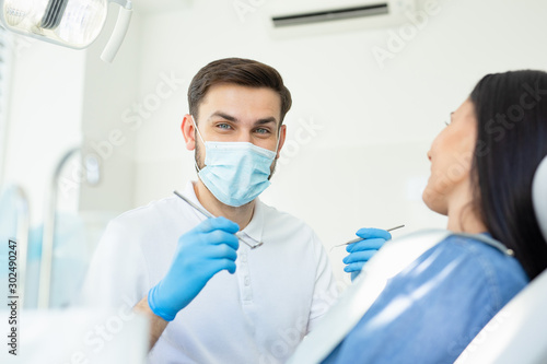 portrait of male dentist looking at the camera in mask and holding instruments for looking client