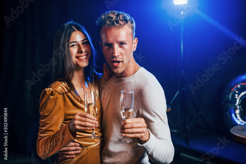 Cute couple stands together at the party with alcohol in hands