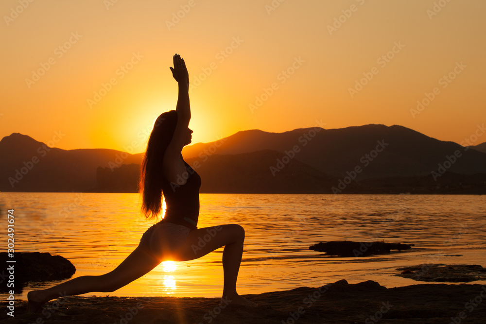 Girl practices yoga in the mountains on the ocean.