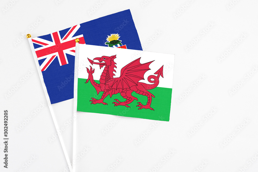 Wales and Cayman Islands stick flags on white background. High quality fabric, miniature national flag. Peaceful global concept.White floor for copy space. Wales and Cayman Islands stick flags on white background. High quality fabric, miniature national flag. Peaceful global concept.White floor for copy space.