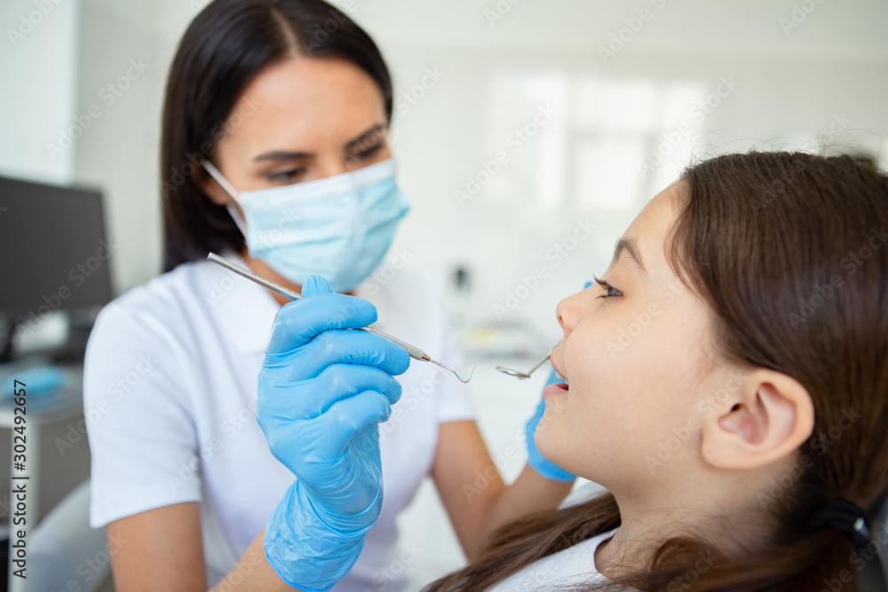 doctor in mask holding instruments for looking client sitting in dental chair doctor in mask holding instruments for looking client sitting in dental chair