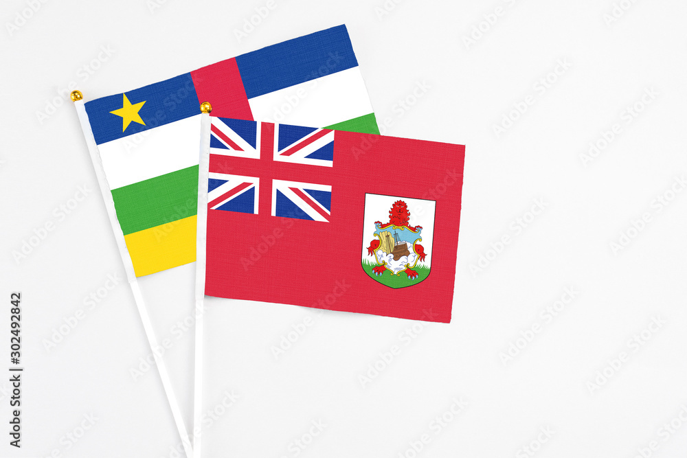 Fototapeta premium Bermuda and Central African Republic stick flags on white background. High quality fabric, miniature national flag. Peaceful global concept.White floor for copy space.