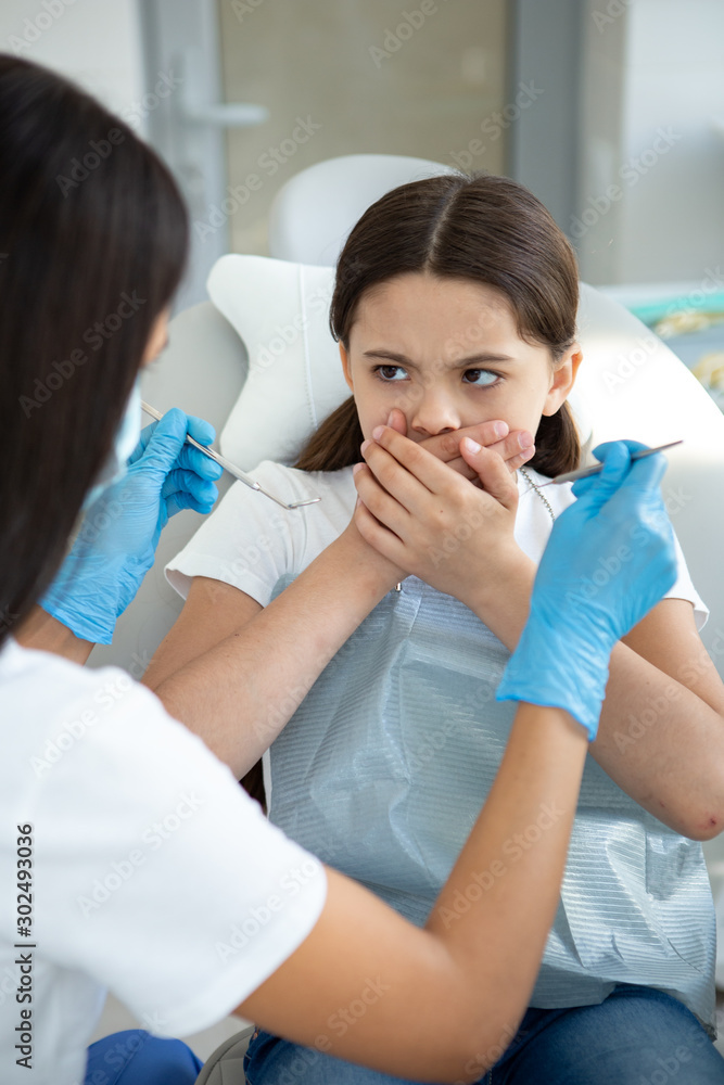 small girl is afraid of dentist in modern dental clinic small girl is afraid of dentist in modern dental clinic