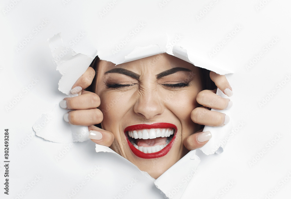 Pretty screaming woman with her eyes closed is struggling to break through a white material wall Pretty screaming woman with her eyes closed is struggling to break through a white material wall