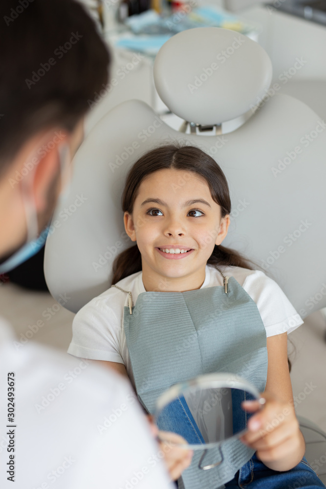 overhead view of smiling small client sitting in dental chair and holding in the mirror on the teeth overhead view of smiling small client sitting in dental chair and holding in the mirror on the teeth