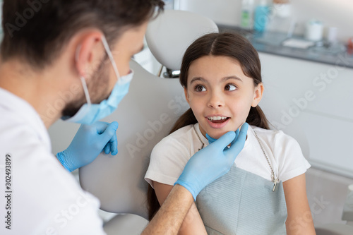 male doctor looking at small client sitting in the dental chair