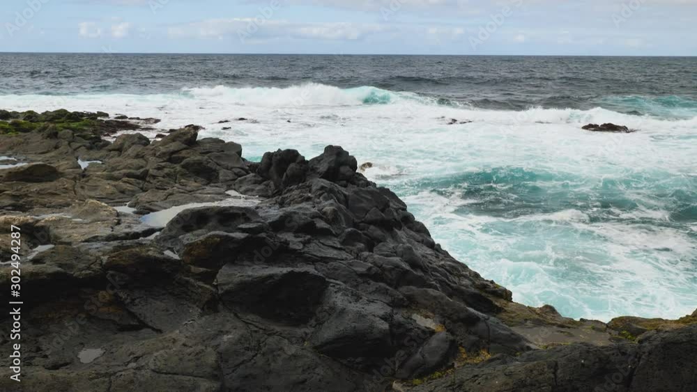 Handheld shot of the waves hitting the rocky beach on an overcast day Handheld shot of the waves hitting the rocky beach on an overcast day