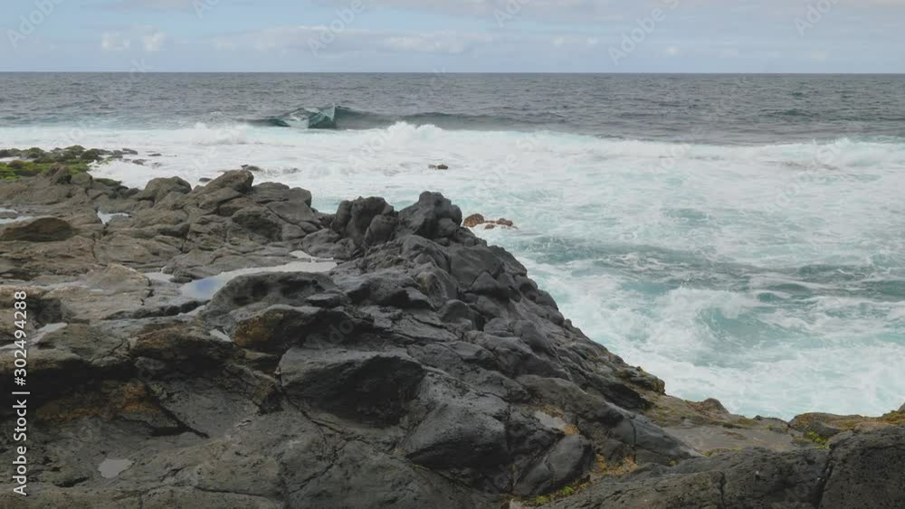 Handheld shot of the waves hitting the rocky beach on an overcast day Handheld shot of the waves hitting the rocky beach on an overcast day