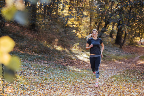 Young sporty woman running in the woods in autumn