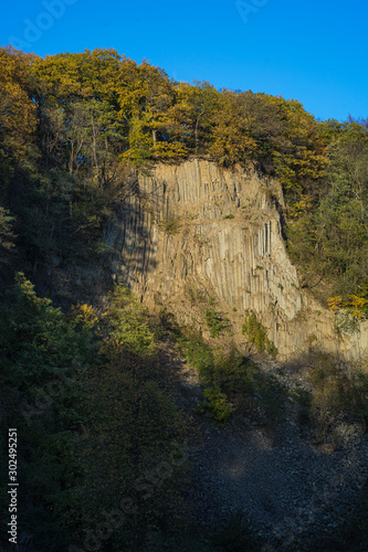 Rock wall at the Weilbergsee with autumn forest in the evening light.