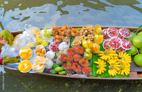 Local people sell fruits, food and souvenirs on boats at Damnoen Saduak Floating Market in Ratchaburi District, Thailand. Famous Asian tourist attraction. photo