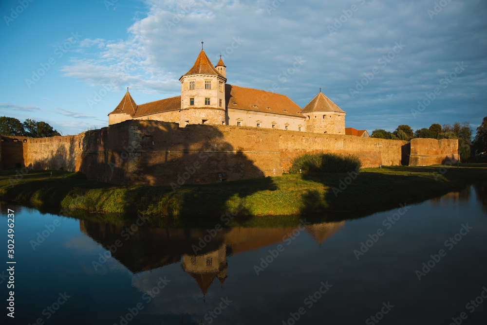 Naklejka premium Beautiful medieval castle with river at sunset somewhere in Romania