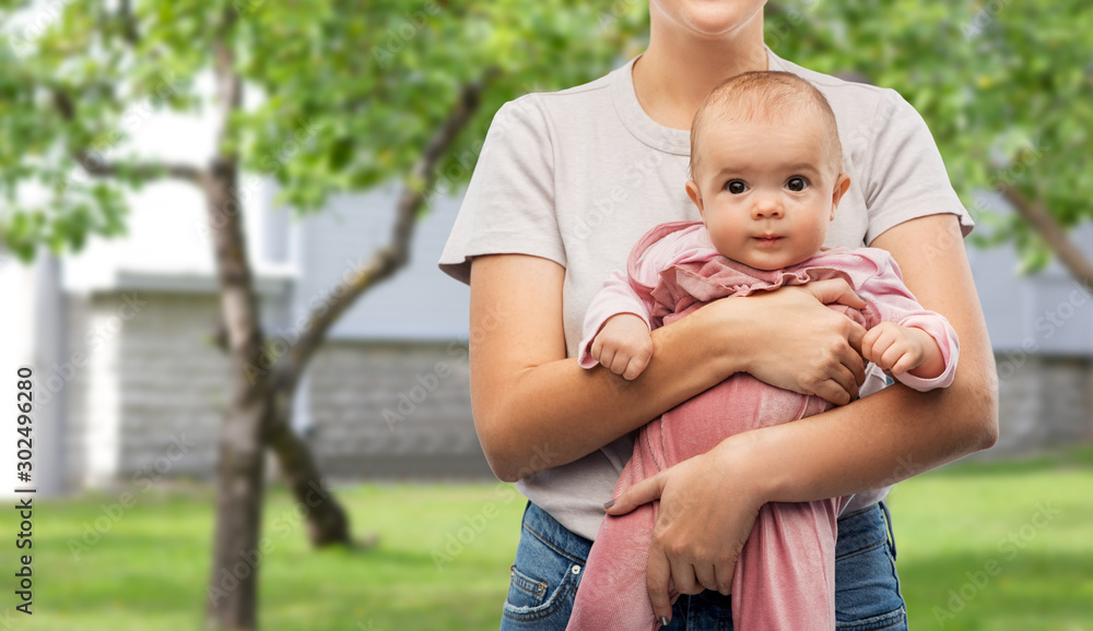 family, child and parenthood concept - happy smiling young mother holding little baby daughter over summer garden or home yard background family, child and parenthood concept - happy smiling young mother holding little baby daughter over summer garden or home yard background