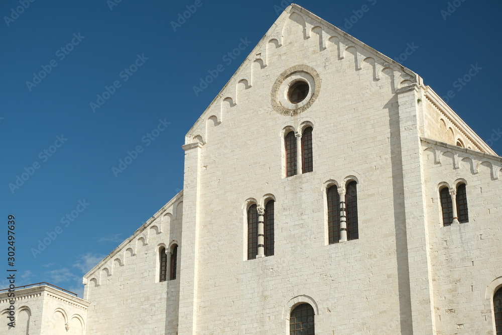Façade of the church of San Nicola in Bari in limestone. Church with light stone walls with the blue sky background with clouds..